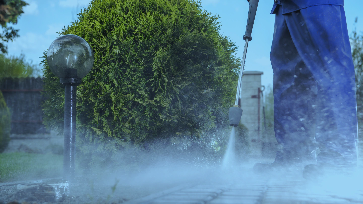 man cleaning a garden using pressure wash