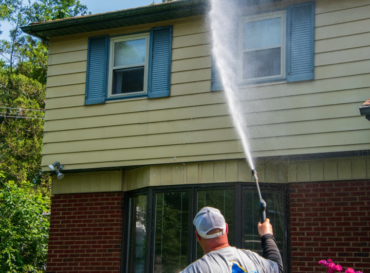 man pressure washing house exterior sidings